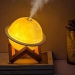 ثلاثة مصابيح على شكل كوكب زحل بألوان إضاءة مختلفة يخرج منها بخار الماء فوق حاملات خشبية بذكاء وبامتياز