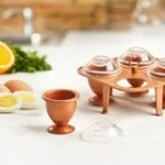 بناءً على الصورة، هذا المنتج هو مجموعة صانعة البيض النحاسية "كوبر شيف" (Copper Chef Copper Eggs)، وهي مصممة لطهي البيض المسلوق أو "البوشيه" بسهولة وبدون الحاجة لتقشيره بعد الطهي. Amazon.eg Amazon.eg +1 المكونات والمميزات الرئيسية: محتويات الطقم: يتكون عادةً من 4 كبسولات (قوالب) نحاسية، 4 أغطية شفافة، وحامل (علاقة) مخصص لوضع القوالب فيه أثناء الطهي. الطلاء: القوالب مزودة بطلاء Cerami-Tech غير اللاصق، مما يسهل خروج البيض منها بعد النضج ويجعل تنظيفها أمراً سهلاً. تعدد الاستخدامات: يمكن استخدامها لعمل البيض المسلوق (جامد، متوسط، أو برشت)، الأومليت، وحتى بعض الحلويات مثل الكريم بروليه والتشيز كيك في الفرن (بدون الأغطية). التنظيف: جميع أجزاء الطقم آمنة للغسل في غسالة الأطباق. Walmart Walmart +5 طريقة الاستخدام (سهلة كما في الصورة 1-2-3): التحضير: يُكسر البيض مباشرة داخل القوالب النحاسية (يمكن دهنها قليلاً بالزبدة أو الزيت لضمان عدم الالتصاق). الإغلاق والطهي: تُوضع الأغطية الشفافة بإحكام على القوالب، ثم تُثبت القوالب في الحامل المخصص.